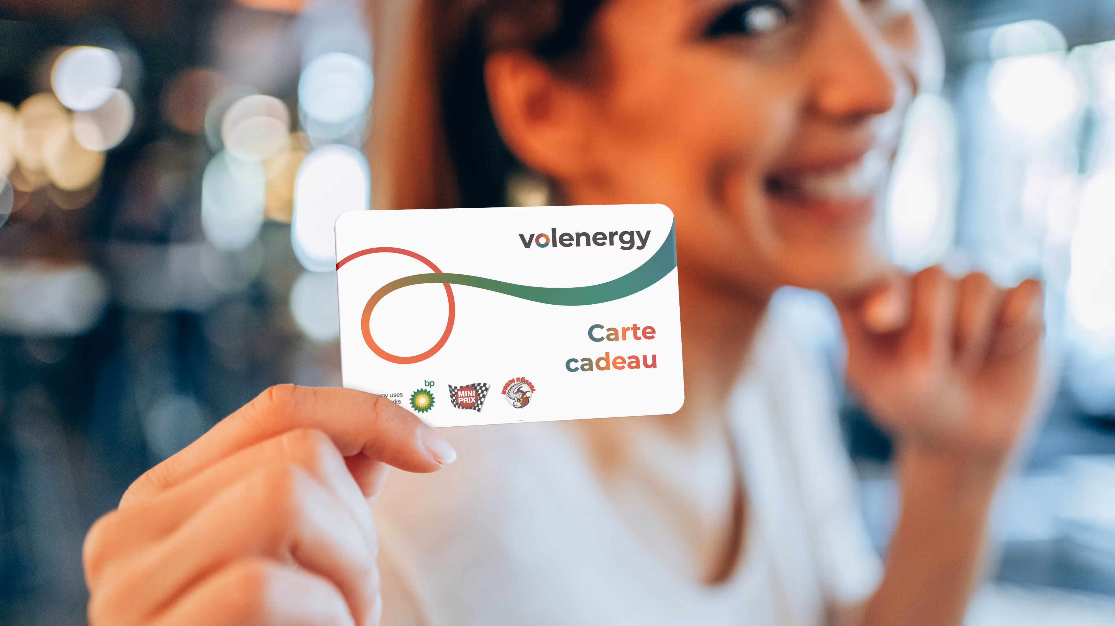 Une femme souriante tient la carte cadeau volenergy devant l'objectif