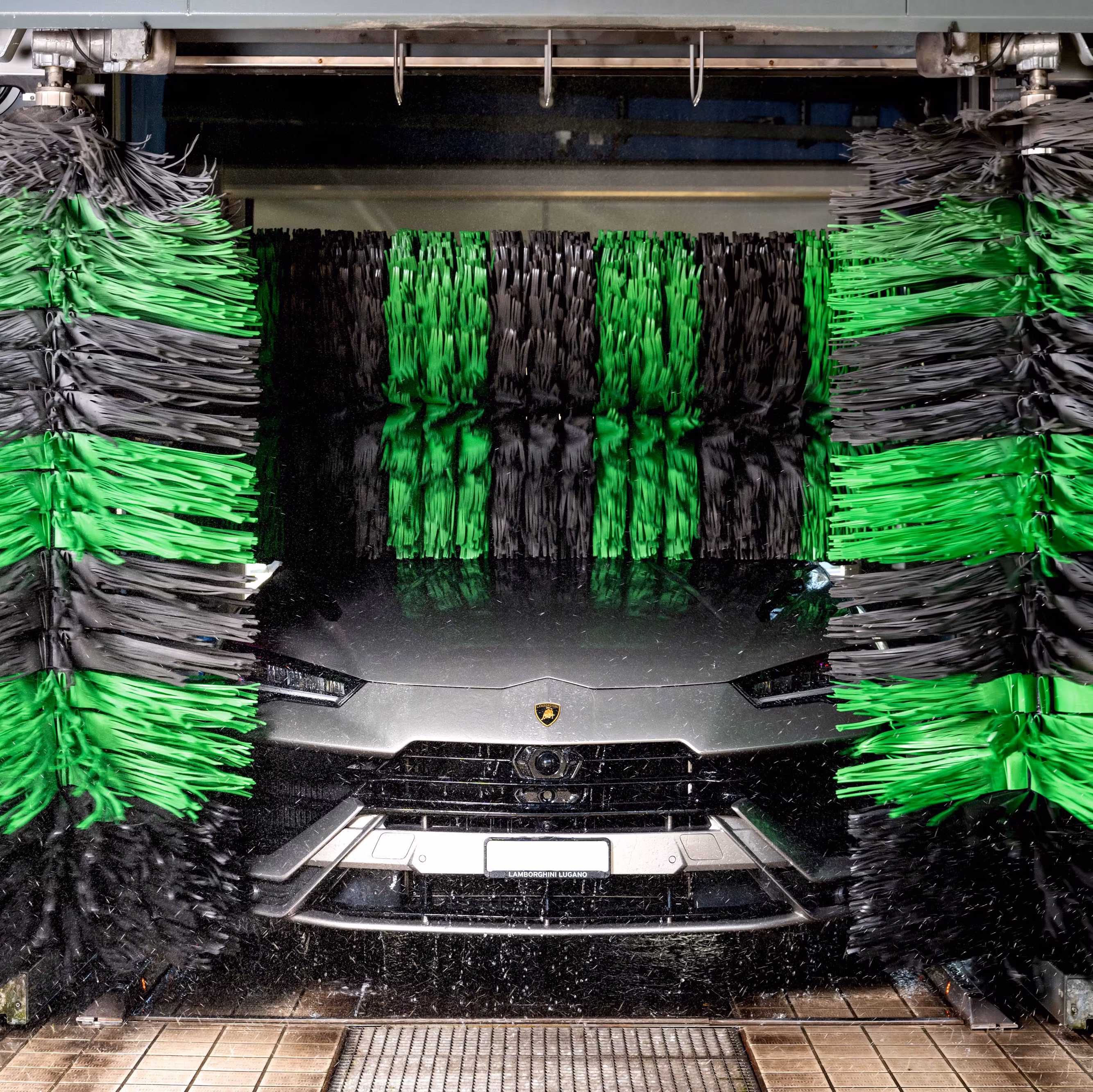 Frontansicht eines Autos, das in einer Waschstrasse von Bürsten sauber geputzt wird