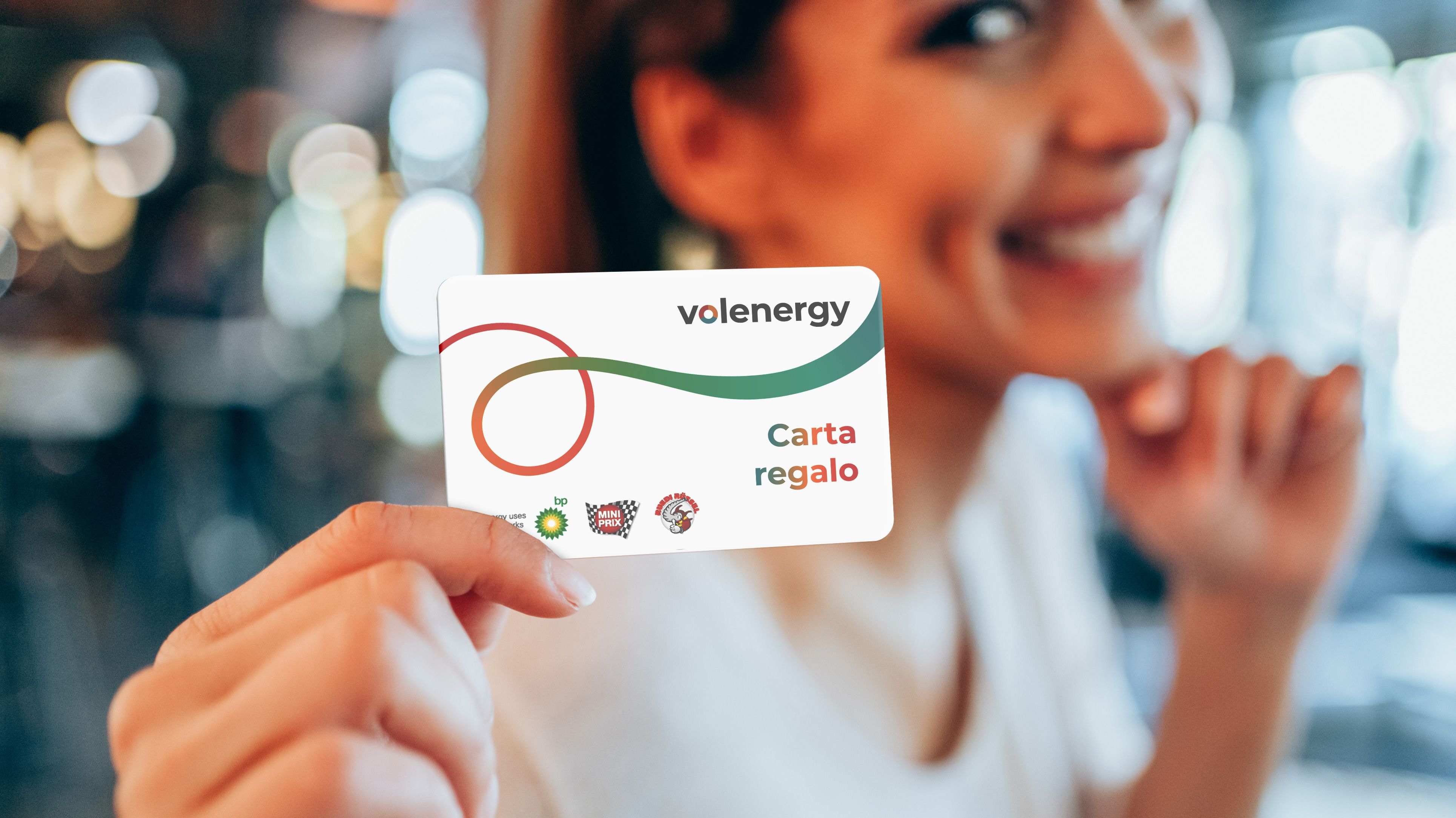 Una donna sorridente mostra la carta regalo volenergy