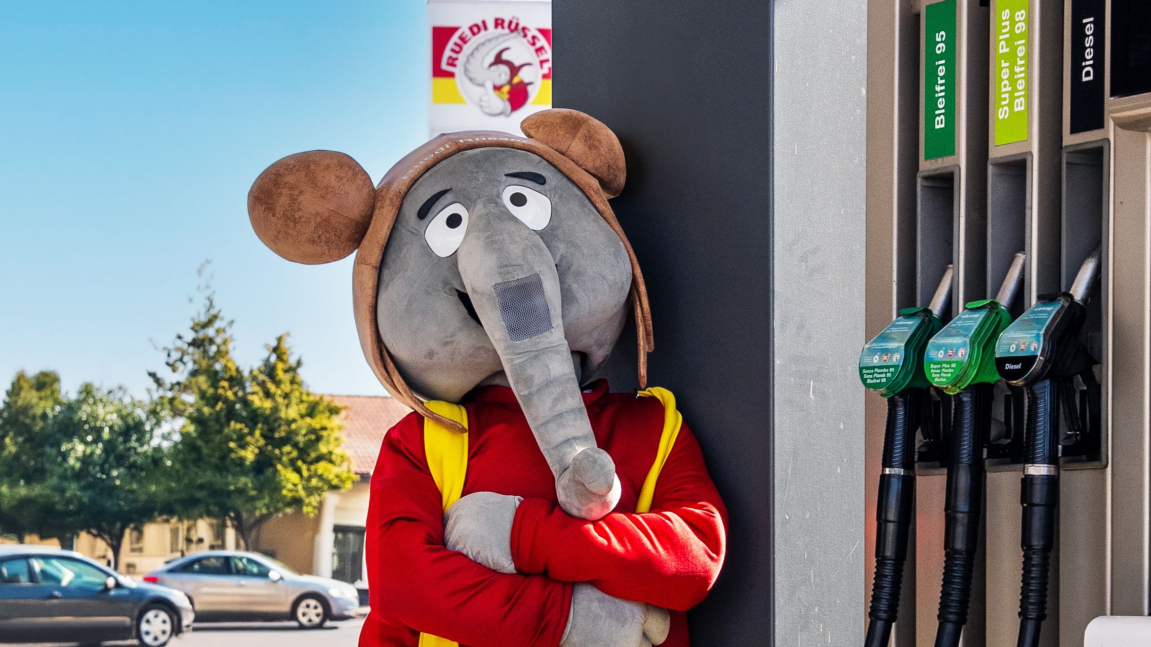 The elephant mascot from volenergy poses casually in a petrol station environment