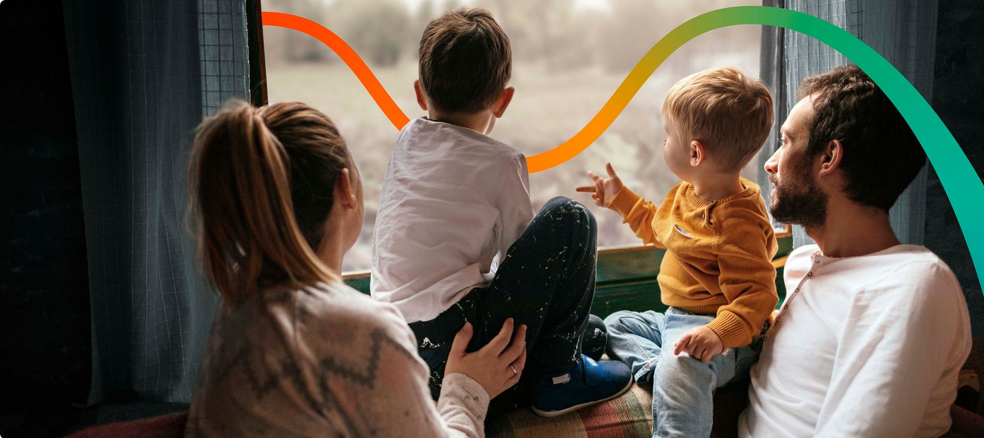 Une femme et un homme assis à la fenêtre avec leurs deux enfants regardent à l’extérieur